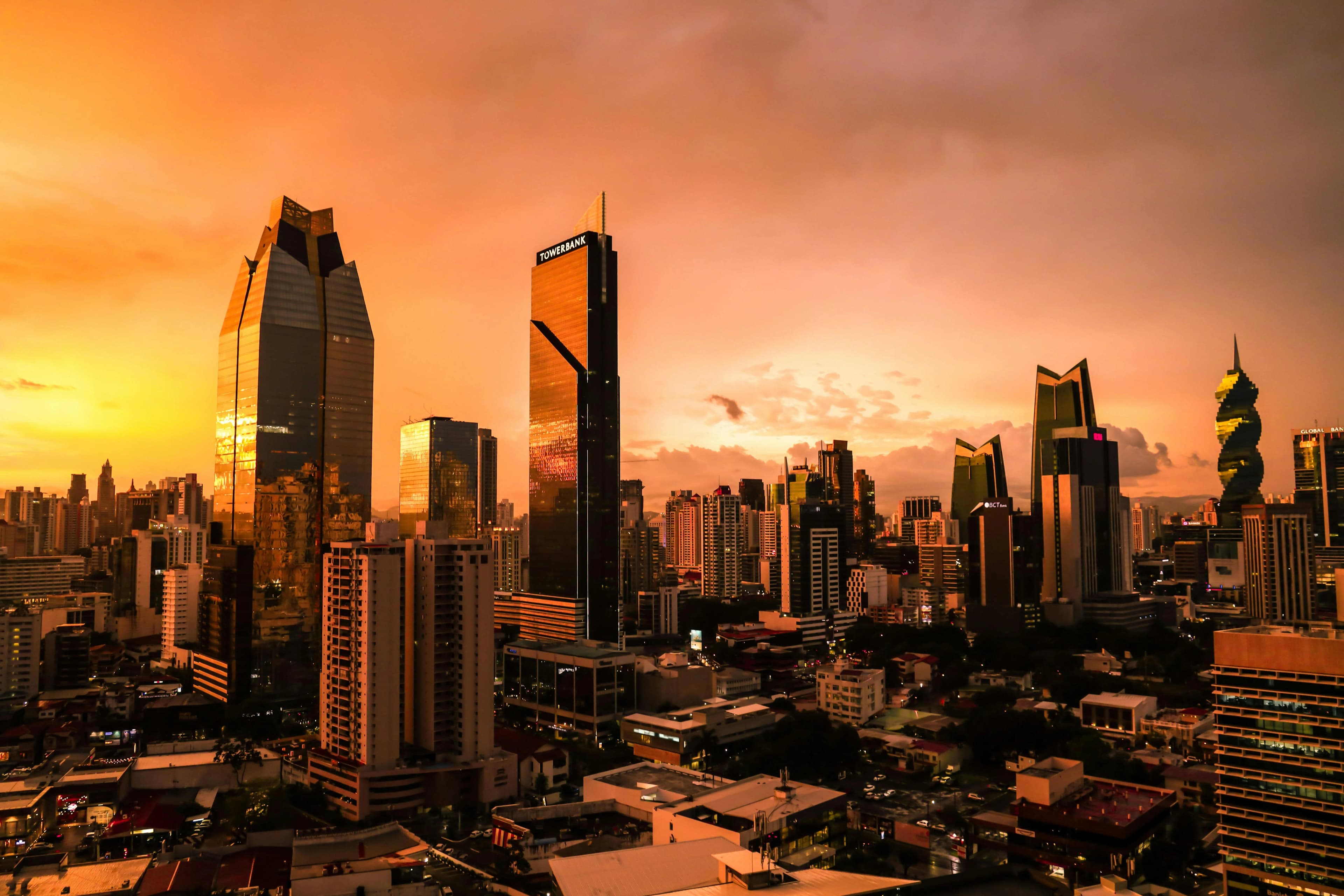 Atardecer sobre el skyline de Ciudad de Panamá con nubes anaranjadas y edificios reflejando la luz